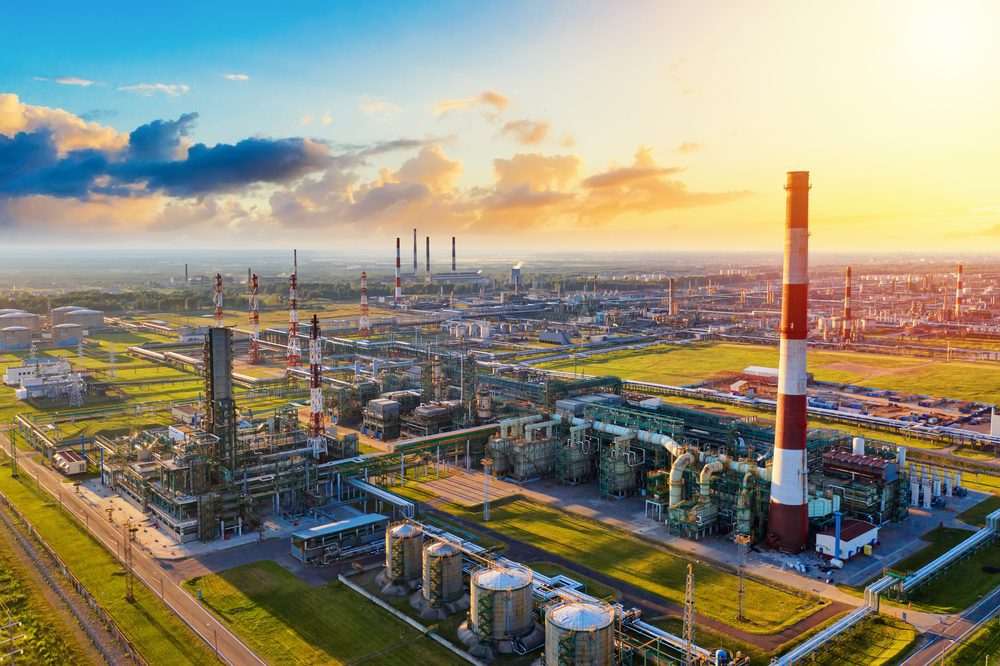 A panoramic aerial view of a sprawling oil refinery complex with many pipes and smokestacks