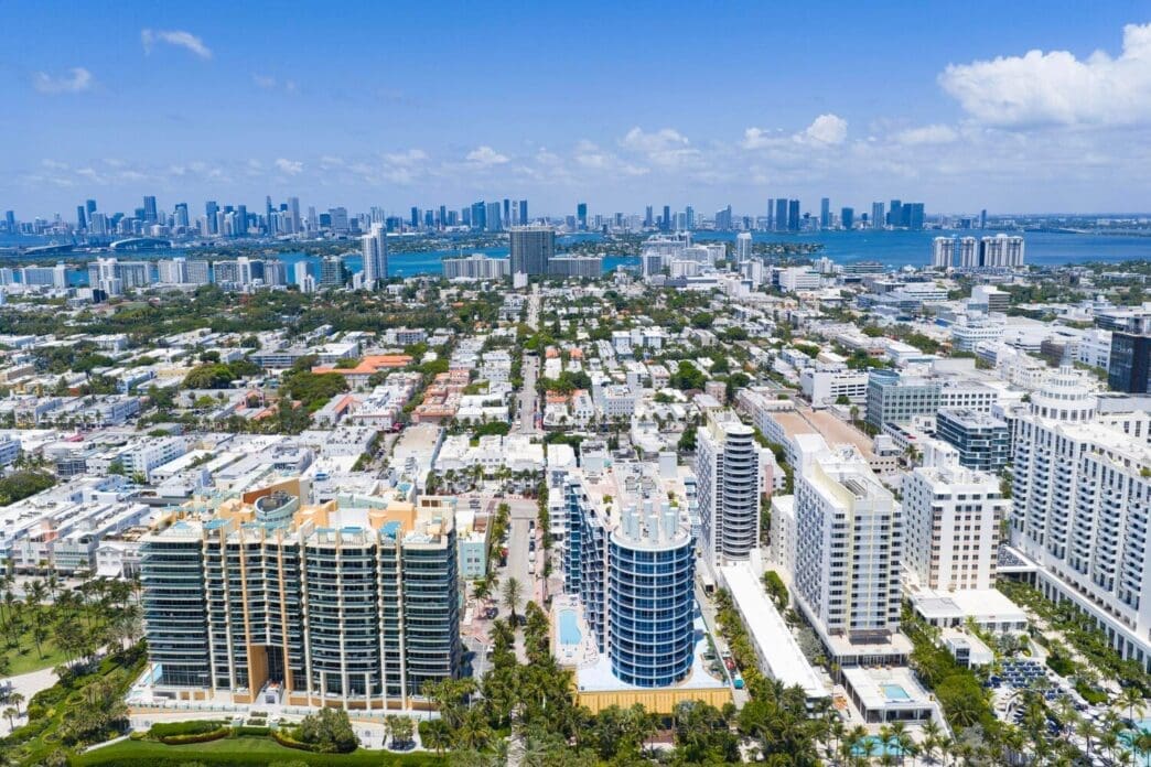 Aerial view of Miami Beach's coastline with skyscrapers and a vibrant cityscape under daylight.