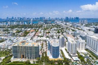 Aerial view of Miami Beach's coastline with skyscrapers and a vibrant cityscape under daylight.