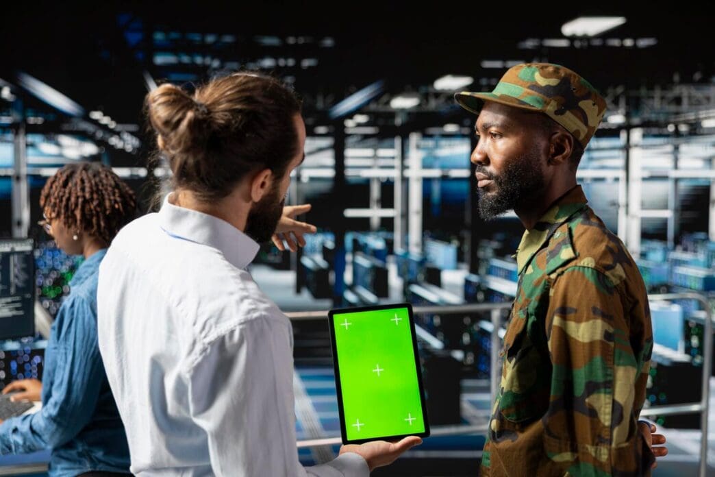 Army soldiers and engineers use a tablet with a green screen.