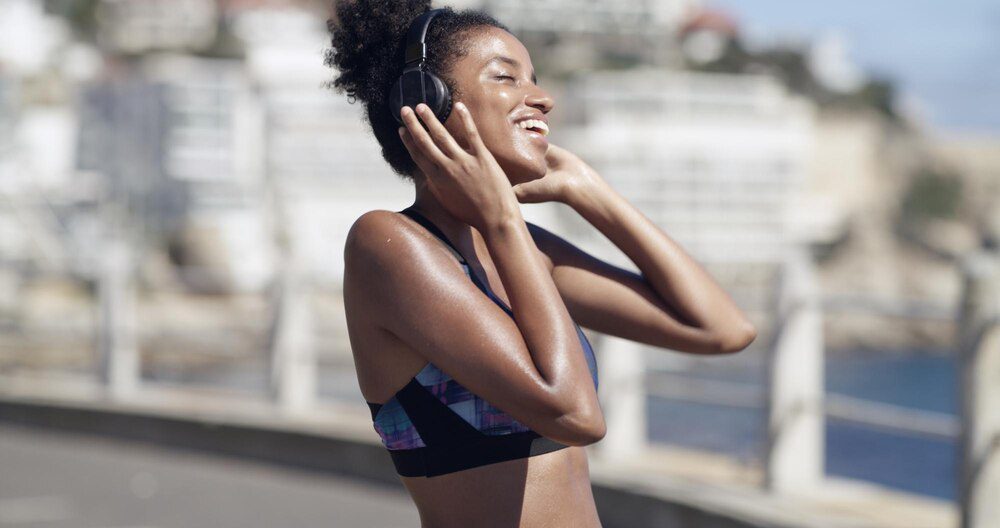 An athlete with headphones listens to music or a podcast while exercising in an urban environment.