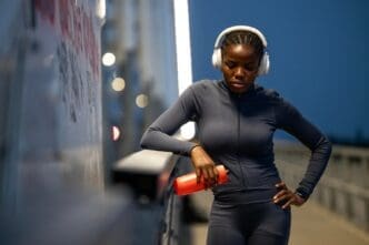 A Black woman in athletic wear focuses intently, preparing mentally for nighttime training.