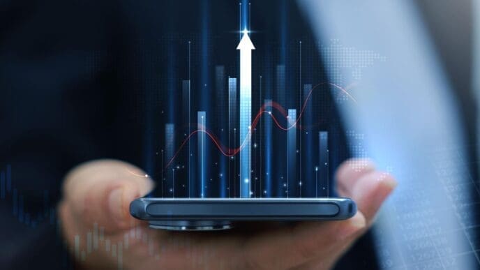 Businessman holding a smartphone displaying a glowing stock market chart with an upward arrow, representing financial growth and investment success.