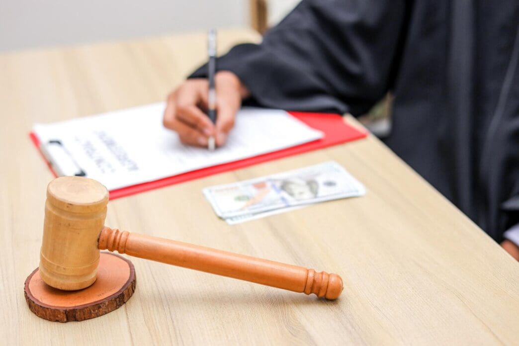 A judge's gavel sits next to a wad of cash on a table, symbolizing the concepts of justice and corruption.