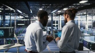 A team leader and worker in a data center review AI performance dashboards.