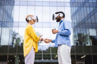 A diverse couple wearing virtual reality headsets shakes hands in front of a modern building, symbolizing technology.