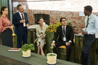 A diverse group of middle-aged professionals networks and socializes during an outdoor meeting.