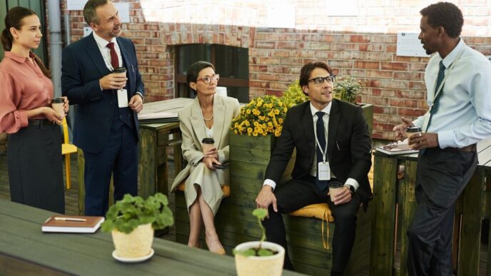 A diverse group of middle-aged professionals networks and socializes during an outdoor meeting.