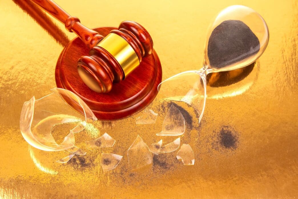 A wooden gavel rests beside a cracked hourglass.