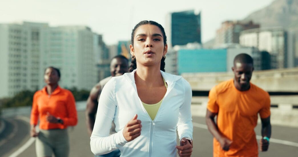 A group of friends runs together through a city, likely training for a marathon or other race.