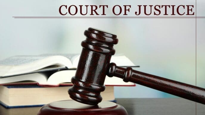 A gavel rests on a table beside a stack of books, all against a light background.