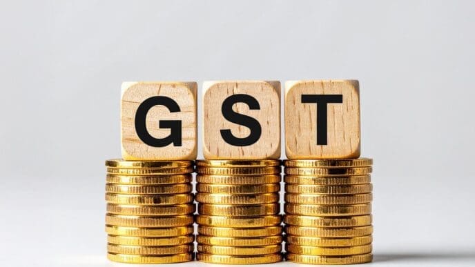 Three gray cubes labeled "GST Concept" are stacked on a surface with several golden coins scattered around them.