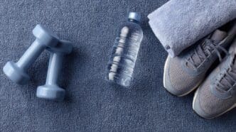 A gray mat displays various gym essentials, such as weights and water bottles.