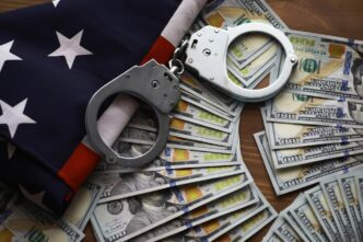 Handcuffs rest on a US flag and dollar bills, symbolizing crime and punishment in America.