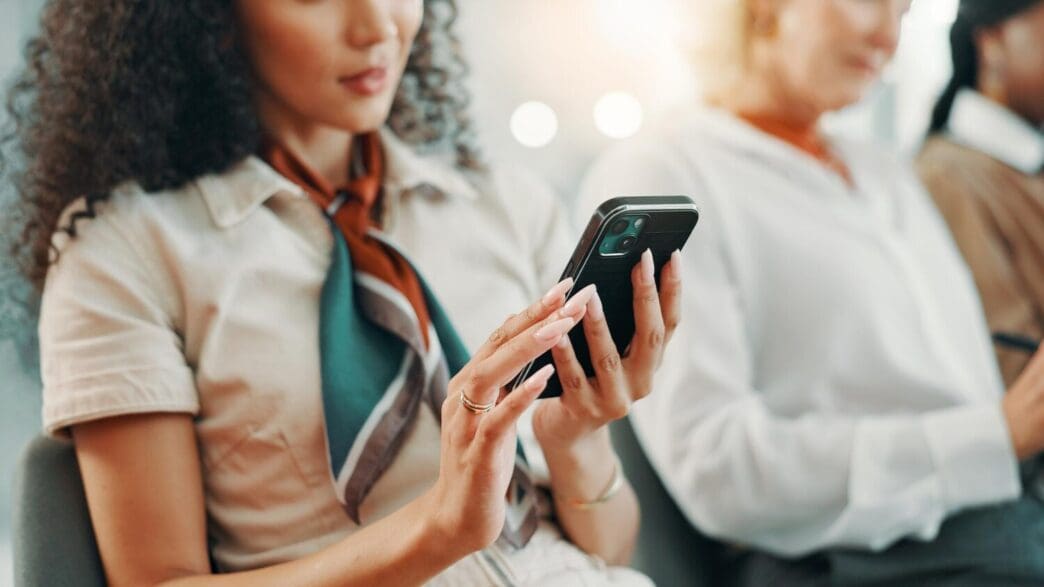 A person in an office setting uses a smartphone, likely for social media research, monitoring, or digital marketing.