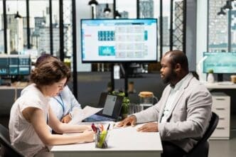 Two HR staff members interview a job seeker in a modern corporate office setting.