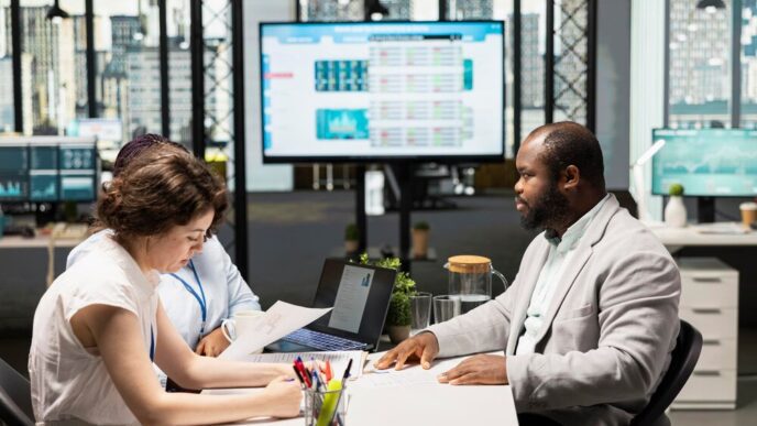 Two HR staff members interview a job seeker in a modern corporate office setting.