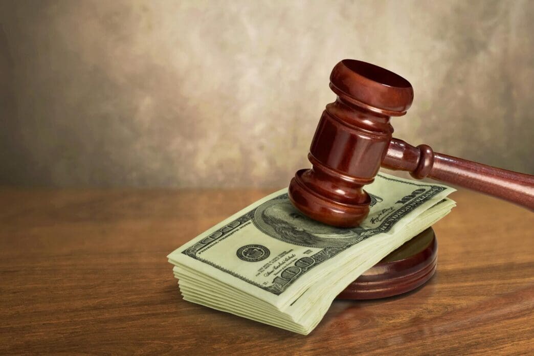 A judge's gavel rests on a wooden table with money visible.