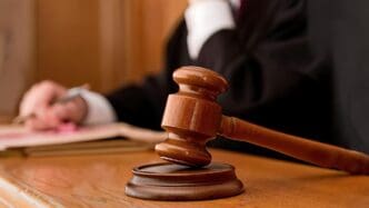A wooden gavel rests on a desk in a courtroom.