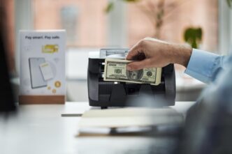 A man in an office counts money using a banknote counter.