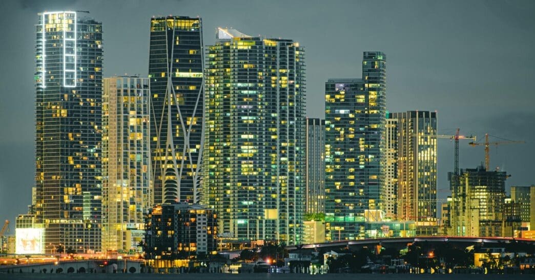 Skyscrapers illuminated at night line the shore of South Beach, Miami.