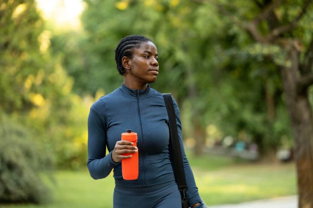 A woman in athletic wear stands outside, appearing ready to begin a workout.