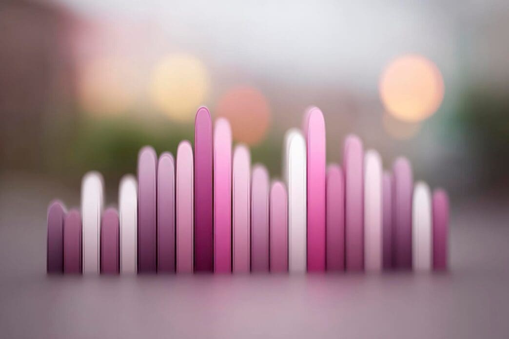Abstract image of pink and purple vertical bars of varying heights against a soft, blurred background.