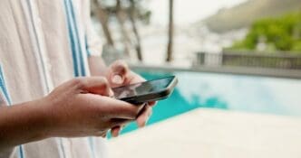 Close-up of a person's hands holding a cellphone, likely in Miami, possibly texting or using social media during a summer holiday.