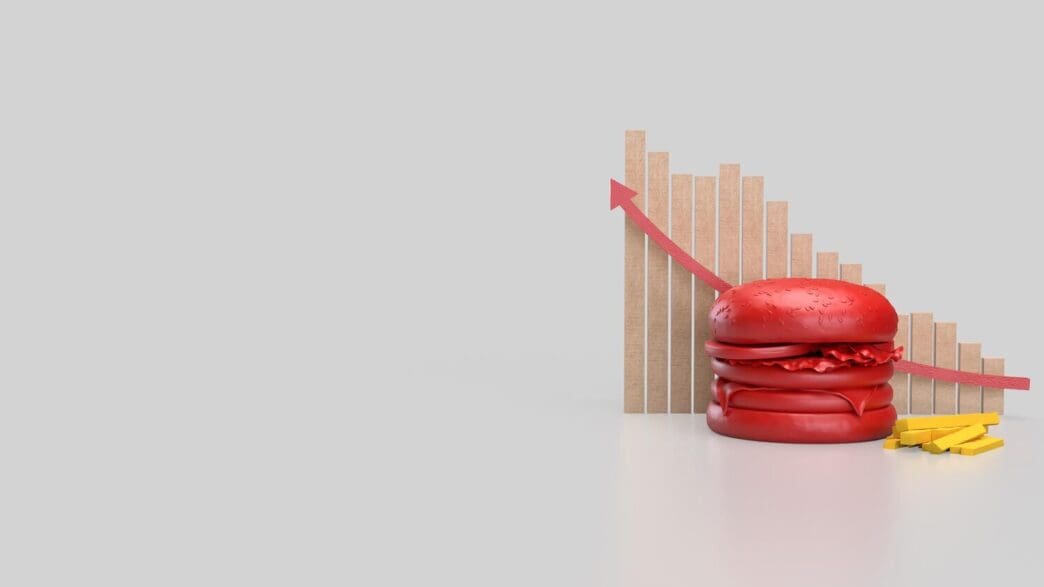 A three-dimensional rendering depicts a red hamburger centered on a white background, likely for use in food or health-related concepts.