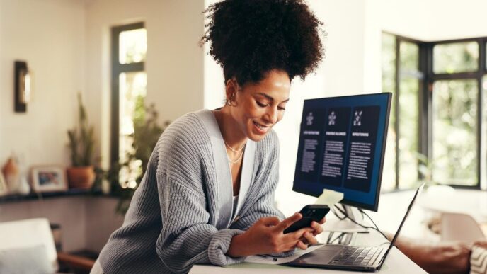 A woman works remotely on a phone and computer in a home office, likely for a consulting business, startup, or project management.