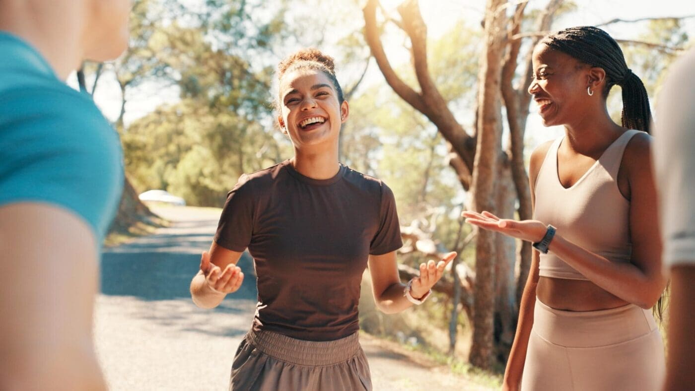 A running coach leads a group of friends on an outdoor workout, encouraging them and laughing together.