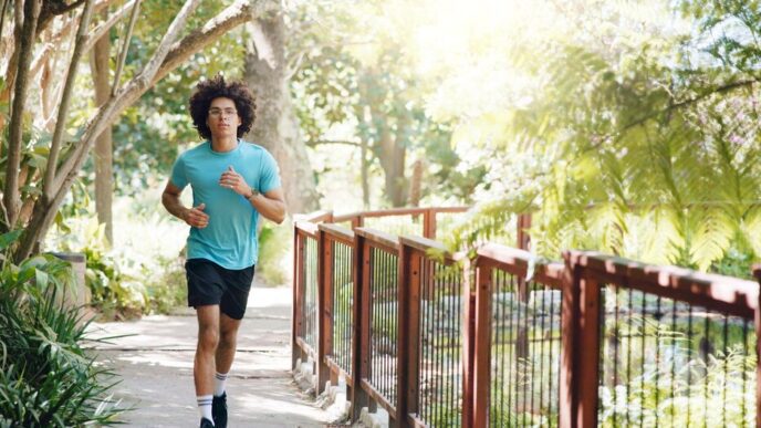 A man runs on a path in a park, engaging in cardio exercise for fitness and marathon training.