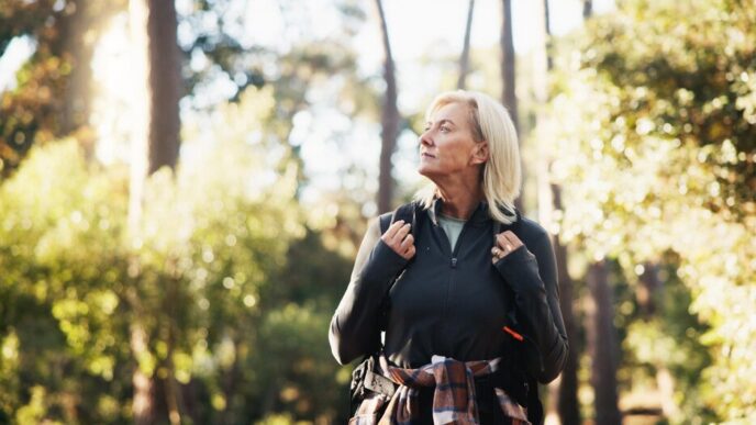 An older woman hikes through a forest.