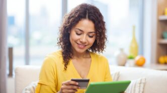 A woman uses a tablet and credit card to shop online.