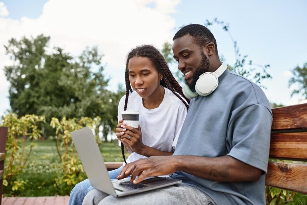 A young couple walks hand in hand on a sunny day, sharing a joyful moment.