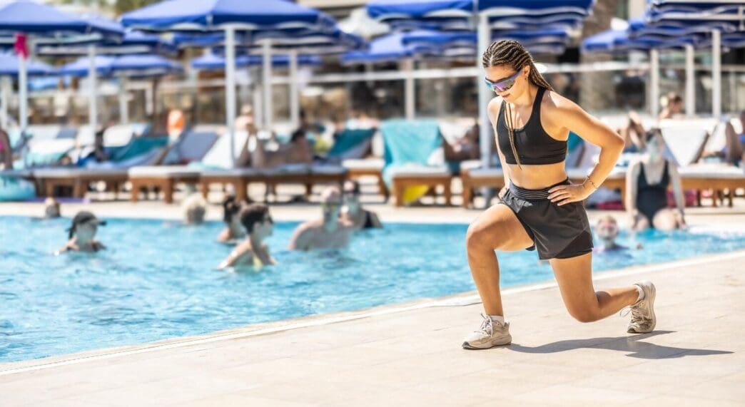 A young woman leads a water aerobics class in a resort pool.