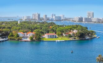 An aerial view of the luxurious homes on Star Island in Miami's Biscayne Bay, with the city skyline in the background.