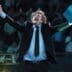 Argentine President Javier Milei with his arms raised in triumph and holding a blue folder, shouting during a conference.
