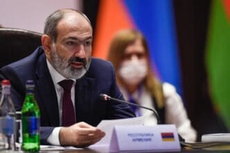 Armenian Prime Minister Nikol Pashinyan speaks at a meeting, with the Armenian flag visible on a table nameplate