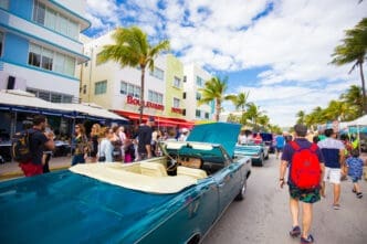 A classic teal convertible car is parked on Ocean Drive in Miami Beach during the Art Deco Weekend antique car show.