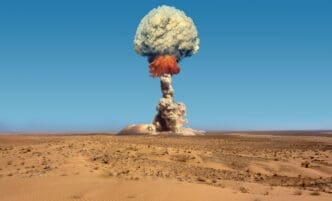 A massive mushroom cloud from a nuclear explosion rises over a desolate desert landscape.