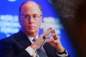 Close-up portrait of Larry Fink, chairman and CEO of BlackRock, wearing a suit and glasses, with his hands clasped.