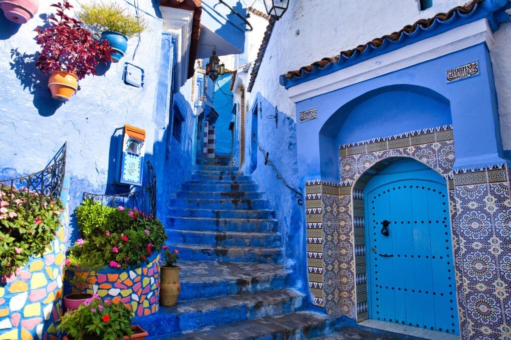 A steep, narrow staircase and arched doorway surrounded by walls painted in brilliant shades of blue in Chefchaouen, Morocco.