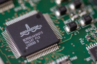 A macro photograph of a black Broadcom ethernet controller microchip soldered onto a green printed circuit board.