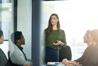 A woman presents to a group of colleagues in a modern office meeting room.