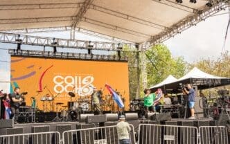 Performers on a large stage with a screen reading "Calle Ocho" at a festival.