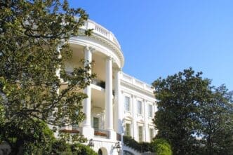 A photo of the White House South Portico on a sunny day, framed by green trees.