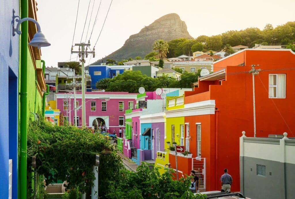 Steep street lined with brightly colored houses in Bo-Kaap, Cape Town, with the prominent Lion's Head mountain in the background.