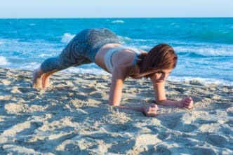 Woman performing a plank exercise on a sandy beach by the ocean