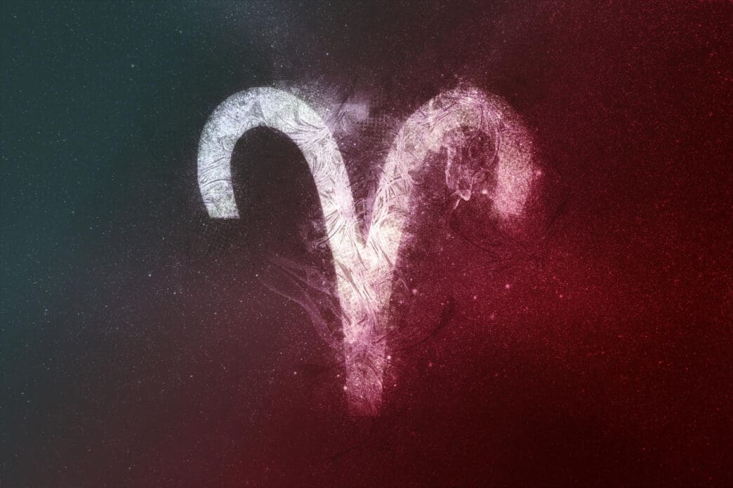 The stylized zodiac symbol for Aries glowing white against a dark cosmic background split into red and teal colors.